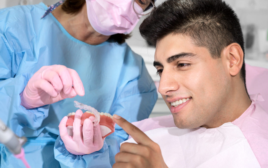 You may be able to use Flexible Spending Accounts for Invisalign treatment. In this image, a dental professional shows a dental patient a clear aligner tray.
