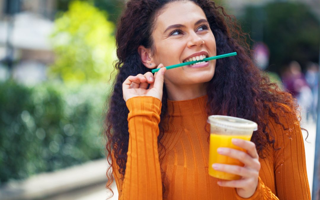 In order to prevent acid erosion of teeth, minimize acid consumption and brush and floss your teeth. In this image, a woman is drinking orange juice, which is an acidic beverage.