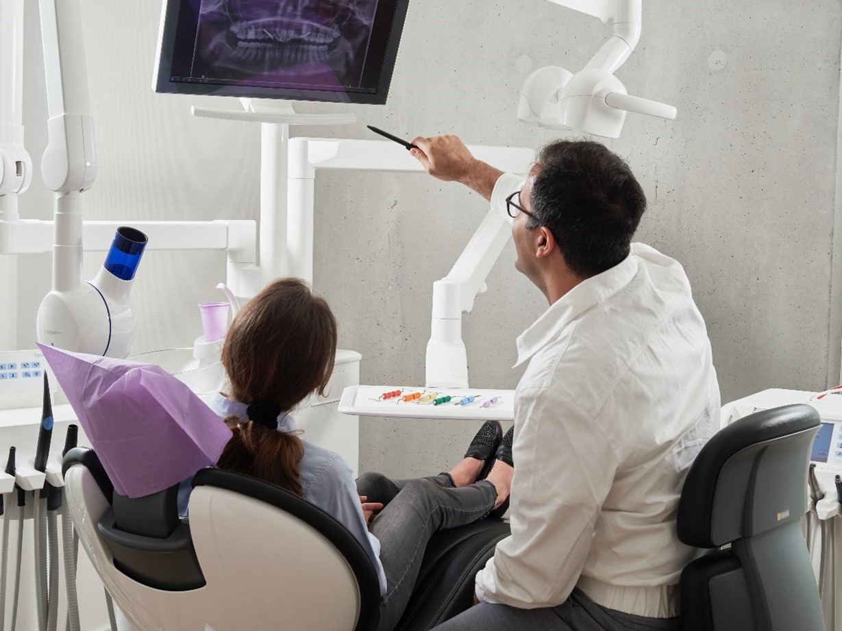 Dentist showing client tooth and cavity x-ray discussing tmj treatment in west Bloomfield.