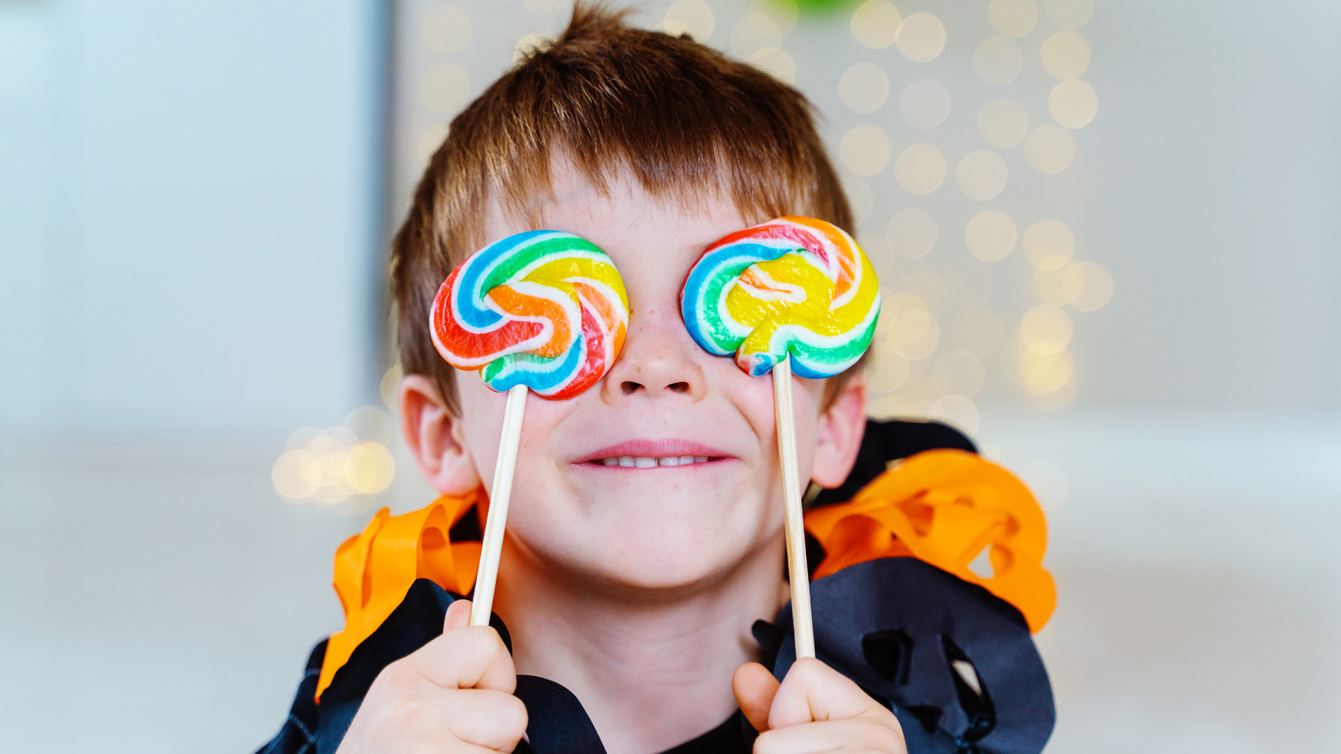 A child holding two lollipops on Halloween, avoid the sugar crash with West Bloomfield Dentist