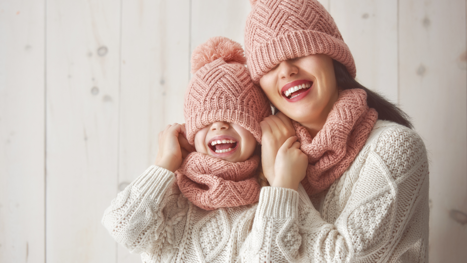 A person and a child wearing hats and scarves and smiling after getting a whitening treatment from Dr. Fienman. professional teeth whitening results for holiday smile
